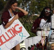 Haleigh Grose, estudiante de 9º grado en Marjory Stoneman Douglas High School, sostiene un letrero que dice: "Nos estás matando", mientras visita la instalación conmemorativa frente a la escuela donde 17 personas fueron asesinadas el 14 de febrero. AFP