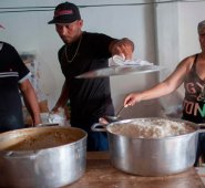 Un inmigrante venezolano (centro) ayuda a los barrios brasileños a preparar comidas para los refugiados venezolanos que viven en la Plaza Simón Bolívar, en Boa Vista, Roraima AFP
