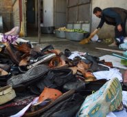 Un hombre limpia un área al lado de un montón de zapatos y sandalias de víctimas afuera del salón de bodas después de una explosión de bomba mortal en Kabul. AFP