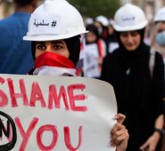 Una mujer manifestante iraquí llevaba un casco de construcción con la palabra "Peaceful" en árabe y marcha con un cartel durante una protesta antigubernamental en Basora, este viernes. AFP