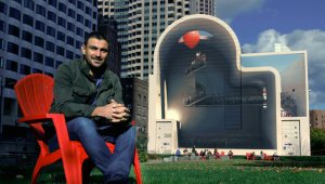 En esta imagen muestra a Mehdi Ghadyanloo, de Teherán, posando ante su mural en el Rose Kennedy Greenway, en Boston. La obra muestra una fila de unas 200 personas, muchas sosteniendo globos rojos de helio, subiendo por una escalera en espiral. AP