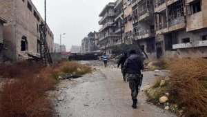 Soldados sirios y combatientes pro-gobierno marchan a través de calles del este de Alepo, Siria. AP
