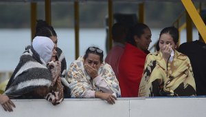 Sobrevivientes del naufragio lloran a medida que aguardan noticias sobre sus seres queridos en Guatapé. AP