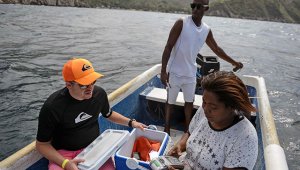 Nancy Rodríguez (derecha) carga una tarjeta de crédito de un turista en un bote, después de conducir a dos kilómetros de la costa de Chichiriviche de la Costa, para encontrar una señal de internet, unos 70 km al noroeste de Caracas. AFP