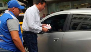 El secretario de Hacienda del departamento, Oscar Gerardino, habla con un conductor para invitarlo a pagar el impuesto del carro. Alfredo Estévez/La Opinión
