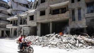 Los hombres en moto pasan los escombros frente a un hospital dañado después de un ataque aéreo en Siria.
 AFP