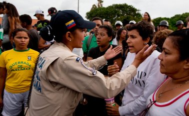 Una mujer policía habla con una multitud enfurecida durante una manifestación por falta de alimentos en el vecindario Catia en Caracas, ocurrida este martes. AP