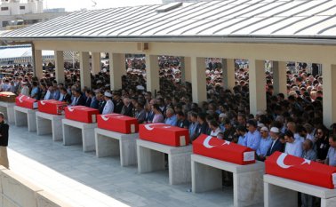 Un oficial de policía hace guardia mientras unas personas rezan durante una ceremonia fúnebre por los policías muertos en el fallido golpe de estado del 15 de julio. AFP