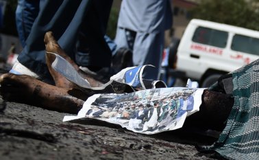 Manifestantes afganos se colocan cerca de los cuerpos de las víctimas en la escena del ataque suicida. Los yihadistas Estado Islámico se atribuyeron dos explosiones. AFP