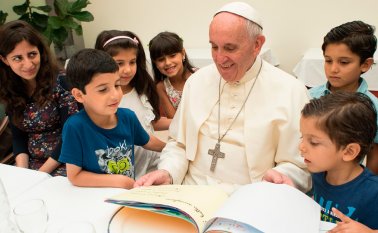 Aquí aparece el papa Francisco observando algunos dibujos, acompañado de niños de familias refugiadas. AP