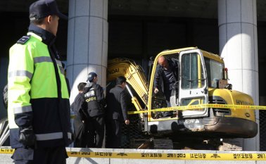Policías examinan una excavadora luego que un hombre arremetiese con ella contra una puerta cerca de la Fiscalía de Seúl. Las autoridades arrestaron al sujeto. AP