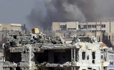 Esta escena tomada de un video proporcionado por la red de noticias Baladi, un medio opositor sirio, muestra el humo alzándose de un ataque sobre una academia militar del gobierno sirio en el oeste de Aleppo, Siria. AP