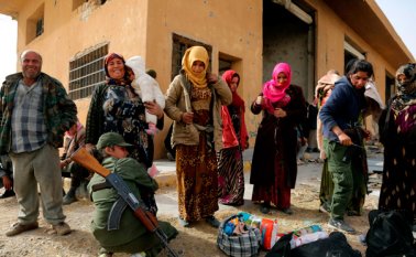 Una policía kurda requisa a mujeres en un campamento de refugiados en el pueblo de Ain Issa, que aloja a personas que huyeron del reducto sirio Raqa. AFP