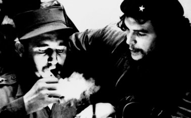 Esta foto de archivo, tomada en la década de 1960, muestra entonces el primer ministro cubano Fidel Castro (izquierda) encendiendo un cigarro mientras escucha al argentino Ernesto Che Guevara. AFP