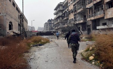 Soldados sirios y combatientes pro-gobierno marchan a través de calles del este de Alepo, Siria. AP