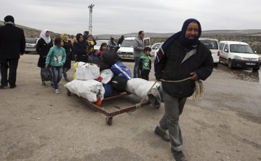 Un sirio lleva sus pertenencias luego de ser evacuado junto con su familia de Alepo, cerca de Idlib, Siria. AP