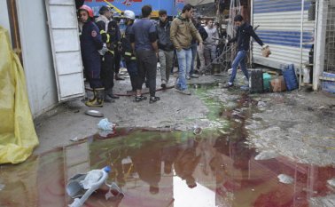 Un grupo de iraquíes se reúne en el lugar del doble ataque suicida en un concurrido mercado del centro de Bagdad. El grupo extremista Estado Islámico se atribuyó la autoría de las explosiones. AP