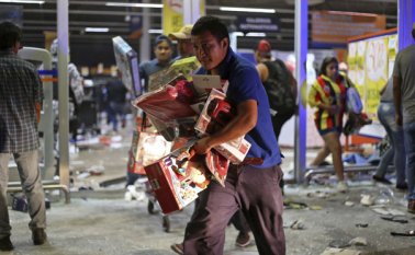 Un hombre corre con juguetes mientras una tienda es saqueada por una multitud en el puerto de Veracruz, México. Las protestas por el aumento brusco del precio de la gasolina irrumpieron en saqueos de gasolineras y tiendas en varias partes. AP