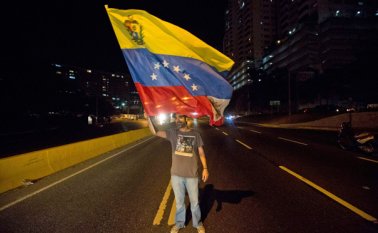 Un dirigente opositor agita una bandera venezolana durante una protesta contra el presidente Nicolás Maduro en Caracas. AP