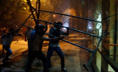 Manifestantes atacan con una barrera el edificio del Congreso durante enfrentamientos con la policía. AP