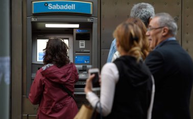 Independentistas catalanes esperaron fuera del cajero automático de CaixaBank, en una gran avenida de Barcelona. AFP