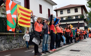 La gente sostiene banderas catalanas independentistas catalanas y banderas del País Vasco cuando participan en una cadena humana entre aldeas en el pueblo vasco norteño de Lazkao AFP