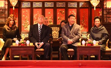 El presidente Donald Trump (izquierda) levanta la vista mientras se sienta junto a la Primera Dama Melania Trump y Xi Jinping (derecha) y su esposa Peng Liyuan. AFP