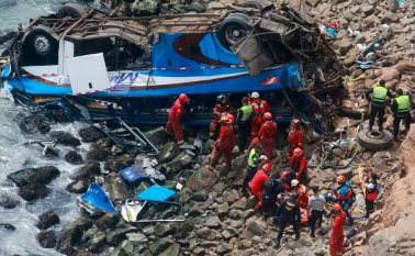 Rescatistas, policías y bomberos durante las labores de auxilio de las víctimas del autobús que se precipitó a a un acantilado, después de colisionar con un camión en una carretera costera cerca de Pasamayo. AFP