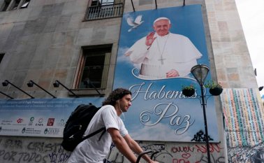 Un hombre pasa en su bicicleta junto a una pancarta con un retrato del papa, en Buenos Aires. Francisco regresa a América Latina por sexta vez en su pontificado. AFP