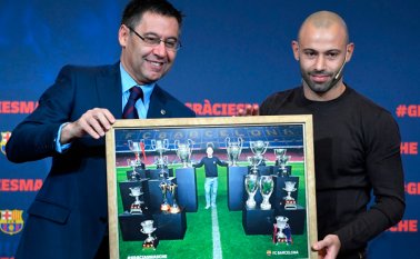 El presedente del Barcelona FC, Josep María Bartomeu (izquierda) y el defensa argentino Javier Mascherano posan con una foto enmarcada de Mascherano y los principales trofeos que ganó con el club de fútbol. AFP