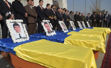 Los empleados de Kam Air se paran frente a los ataúdes de sus colegas, todos empleados ucranianos de la aerolínea afgana, en una ceremonia en el Aeropuerto Internacional de Kabul, tras su muerte en el ataque talibán. AFP