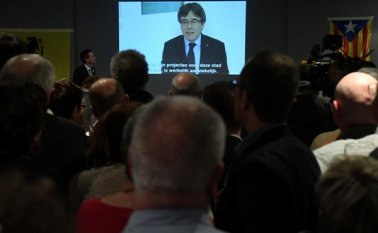 La gente ve en pantalla una transmisión en vivo de un discurso del destituido líder separatista catalán Carles Puigdemont. AFP