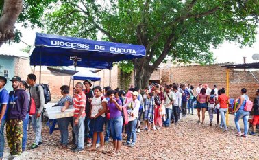 En orden, los inmigrantes venezolanos se forman para recibir el apoyo alimenticio de la Casa de Paso. Cortesía