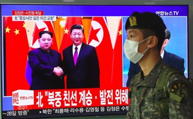Un soldado surcoreano pasa ante un televisor en una estación de ferrocarril en Seúl que informa sobre la visita a China del líder norcoreano Kim Jong Un (izquierda),  quien aparece junto al presidente Xi Jinping. AFP