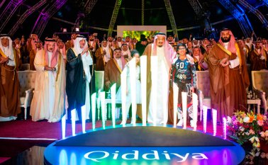 El rey Salman bin Abdulaziz abraza a dos niños detrás del logotipo de ‘Qiddiya’, lugar en donde se construirá la ‘ciudad de entretenimiento’, que abarca 334 kilómetros cuadrados. AFP