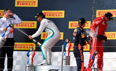 Lewis Hamilton (segundo a la izquierda) rocía champán a un miembro de Mercedes en el podio junto al segundo clasificado, el piloto holandés Max Verstappen (segundo derecha) y el piloto finlandés Kimi Raikkonen. AFP