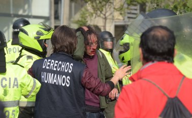 Un delegado universitario de derechos humanos intercede después de que un estudiante resultó herido durante los enfrentamientos con la policía antidisturbios.
 AFP