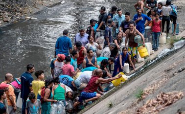 Miles de venezolanos, en medio de la desesperación y la angustia por la falta de agua, acuden a los contaminados ríos para recoger el líquido y enfrentar así la tremenda falta de los últimos días. AFP
