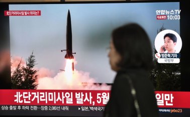 Una mujer pasa frente a una pantalla de noticias de televisión, que muestra imágenes de archivo de un lanzamiento de misiles de Corea del Norte, en una estación de tren en Seúl. AFP