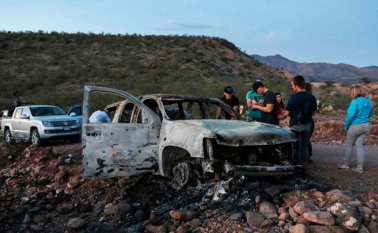 Miembros de la familia Lebaron observan el auto quemado donde parte de los nueve miembros asesinados de esta familia fueron asesinados y quemados durante una emboscada de hombres armados. AFP
