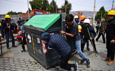 Manifestantes mueven un contenedor de basura para bloquear una calle en La Paz. AFP