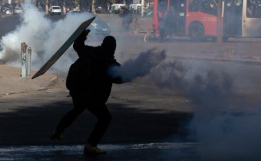 Un manifestante arroja un bote de gas lacrimógeno contra la policía antidisturbios durante una protesta.
 AFP