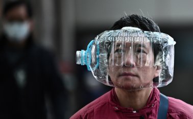 Una mujer usa una botella de agua de plástico con un recorte para cubrirse la cara, mientras camina por una pasarela en Hong Kong, el 31 de enero de 2020, como medida preventiva ante el coronavirus. AFP