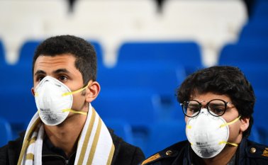 Los fanáticos del fútbol asisten con máscaras a los estadios por el brote de coronavirus. AFP