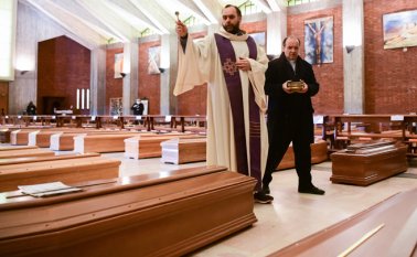 El sacerdote Don Marcello da una bendición a los ataúdes de las personas fallecidas dentro de la iglesia de San Giuseppe en Seriate, Italia, el 28 de marzo de 2020. AFP