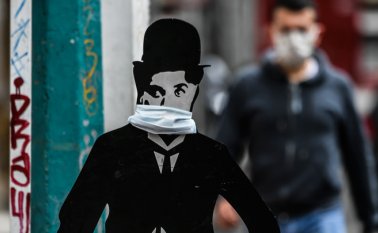 Una imagen en tamaño real del actor cómico inglés Charles Chaplin usa una máscara facial en una calle de Bogotá, este martes, en medio de la propagación del nuevo coronavirus, COVID-19. AFP