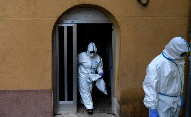 Los trabajadores sanitarios de los Servicios de Emergencias Médicas de Madrid (SUMMA 112) con trajes protectores llegan al hogar de una persona que cayó enferma. AFP