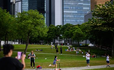 En Hong Kong la gente visita el Parque Tamar tras el anuncio de medidas para aliviar el confinamiento y el distanciamiento social. AFP