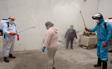 Trabajadores del gobierno local de Xochimilco, en México, desinfectan a una mujer y su casa como medida preventiva contra la propagación del nuevo coronavirus. AFP