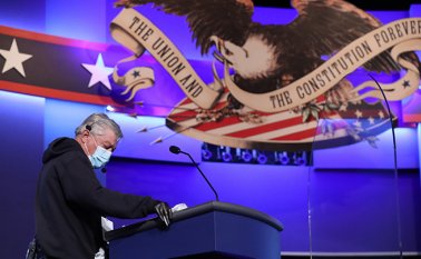 Un hombre desinfecta el escenario donde se hará el debate. AFP